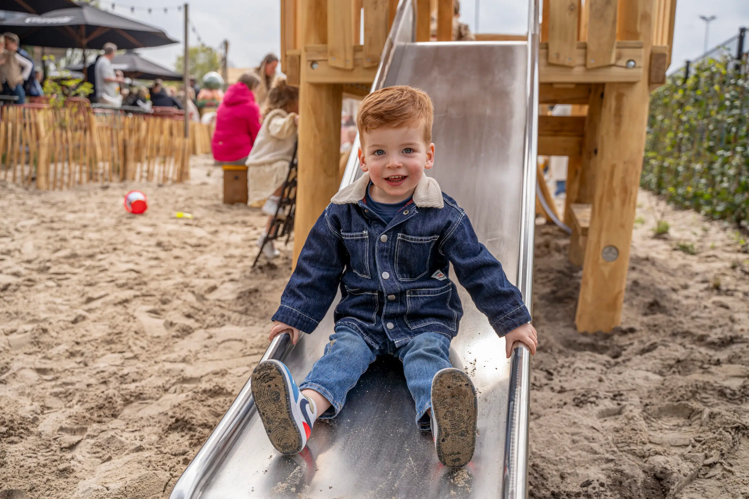 Schattig jongetje die van de glijbaan afgaat in de speeltuin