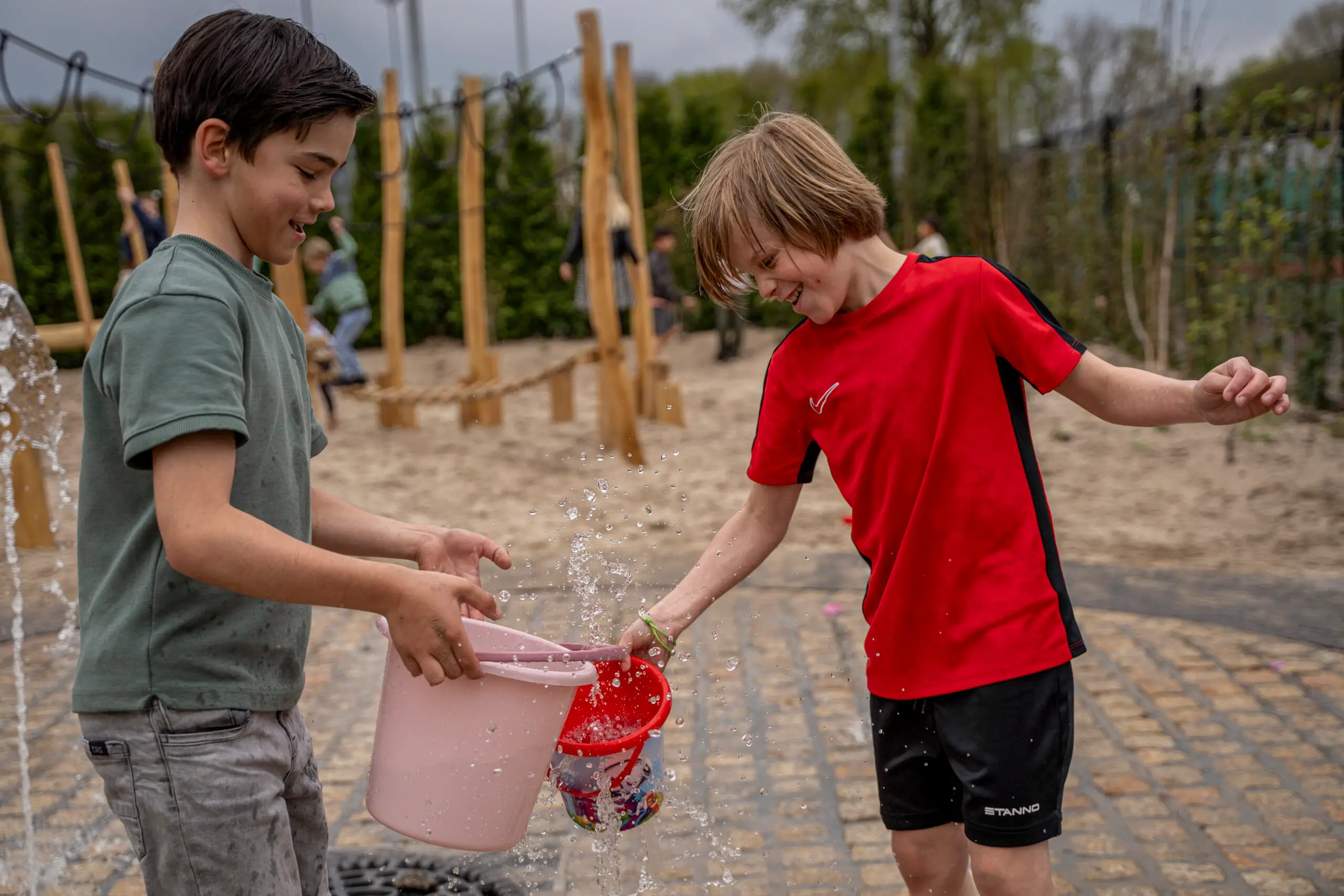 Twee jongens die met water spelen in de speeltuin in Vlijmen