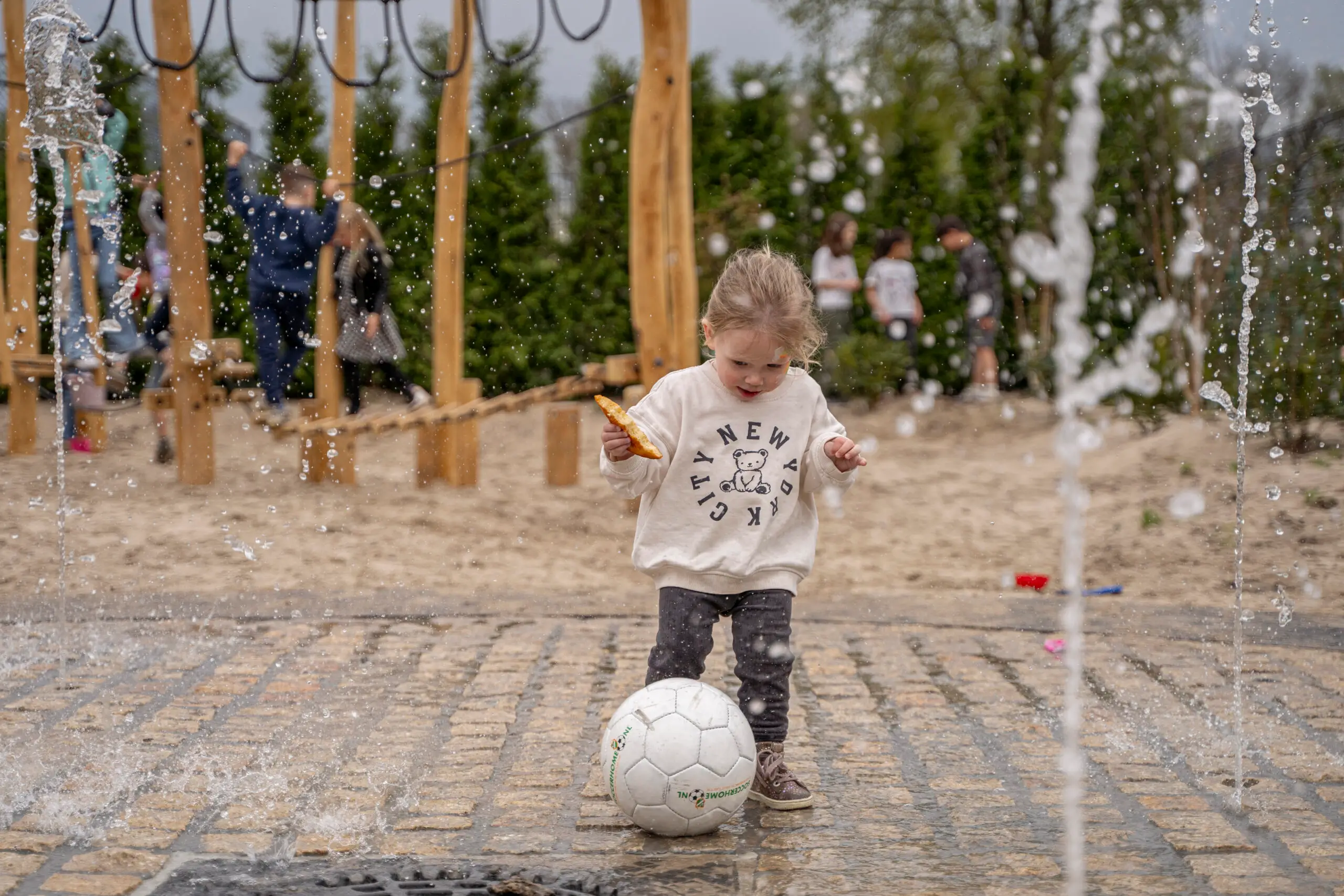 Schattig meisje in de speeltuin met een voetbal