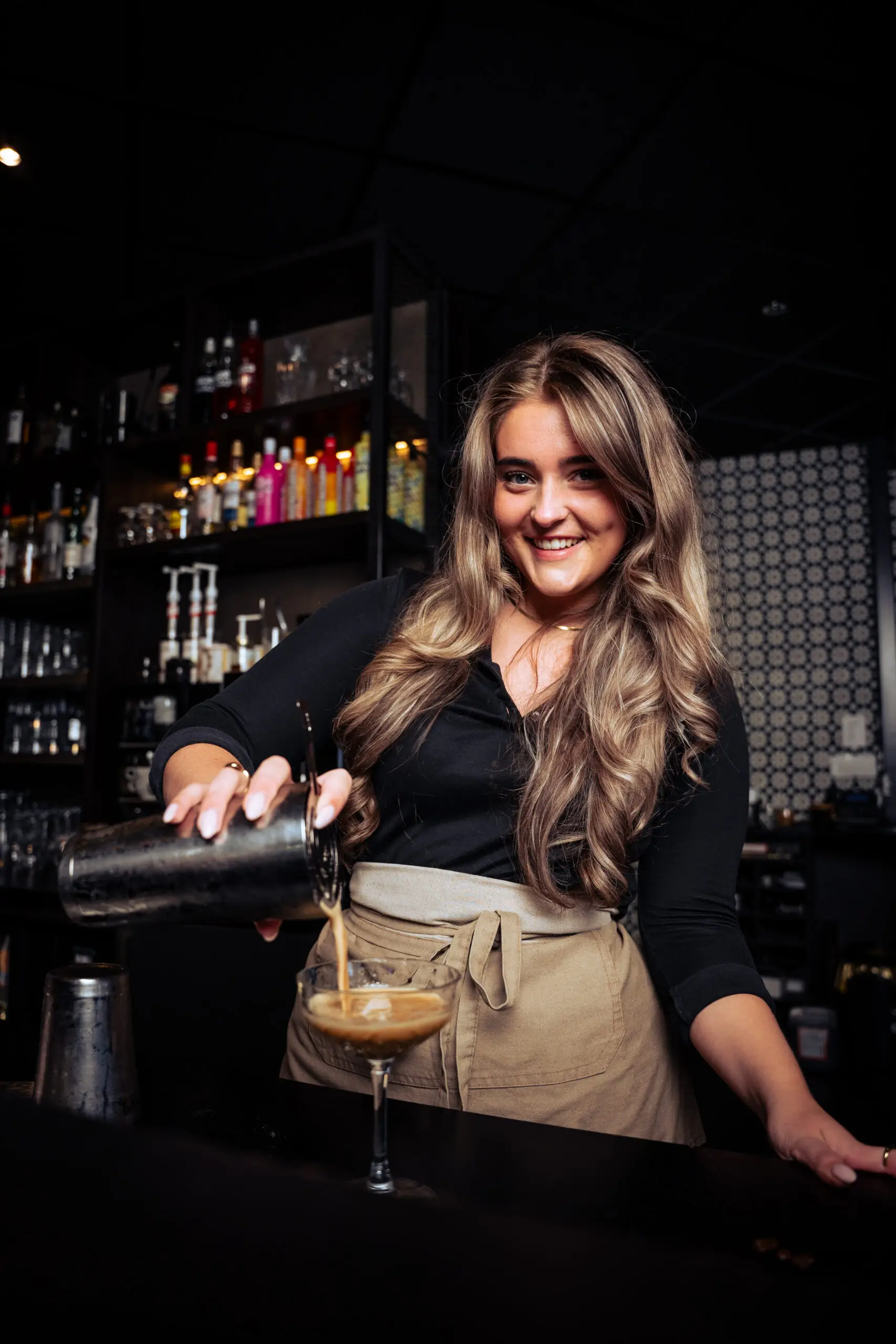 Barmedewerkster die een cocktail inschenkt - collega's