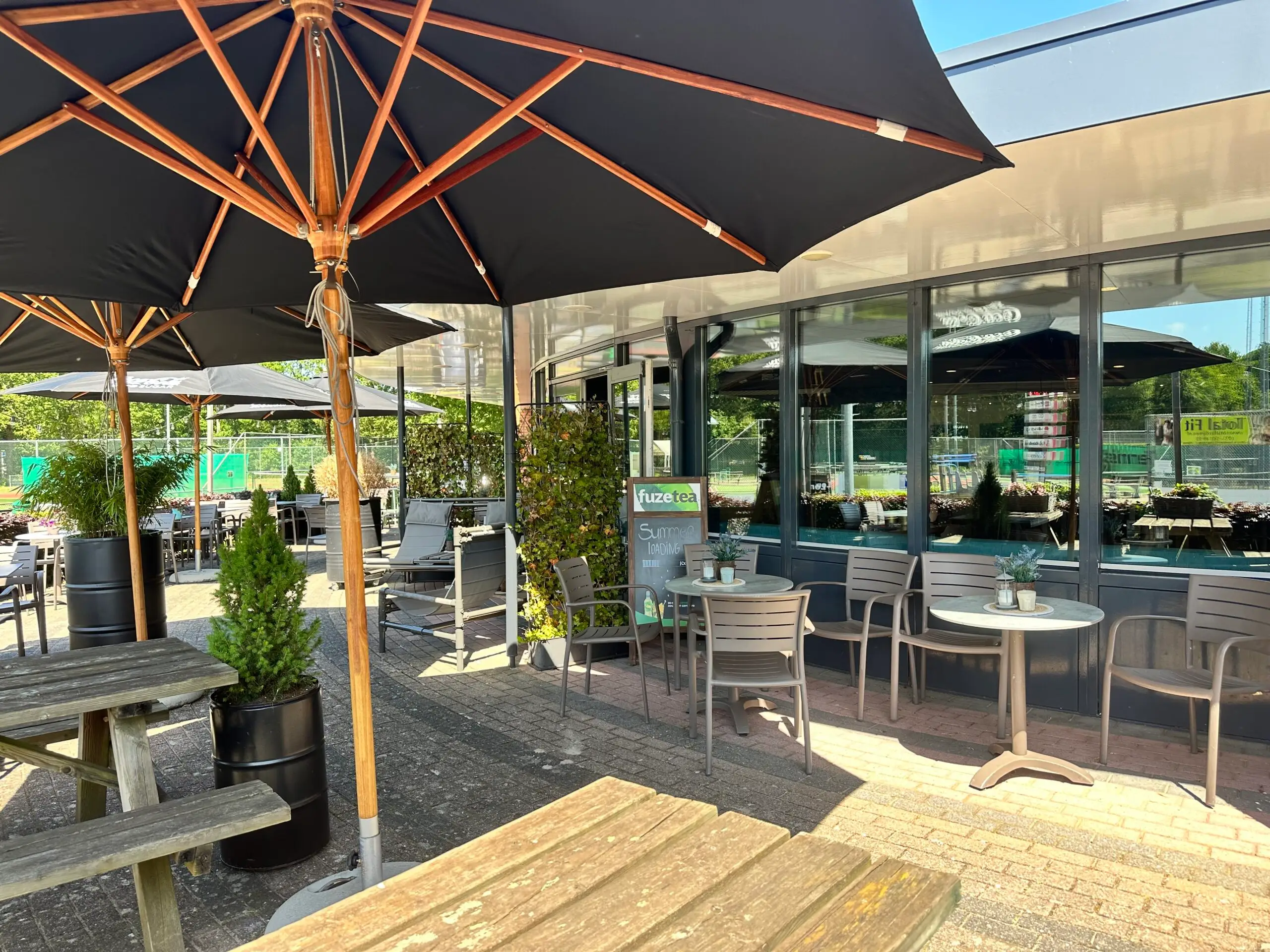 Terras met picknicktafels, stoelen, ronde tafels en parasols