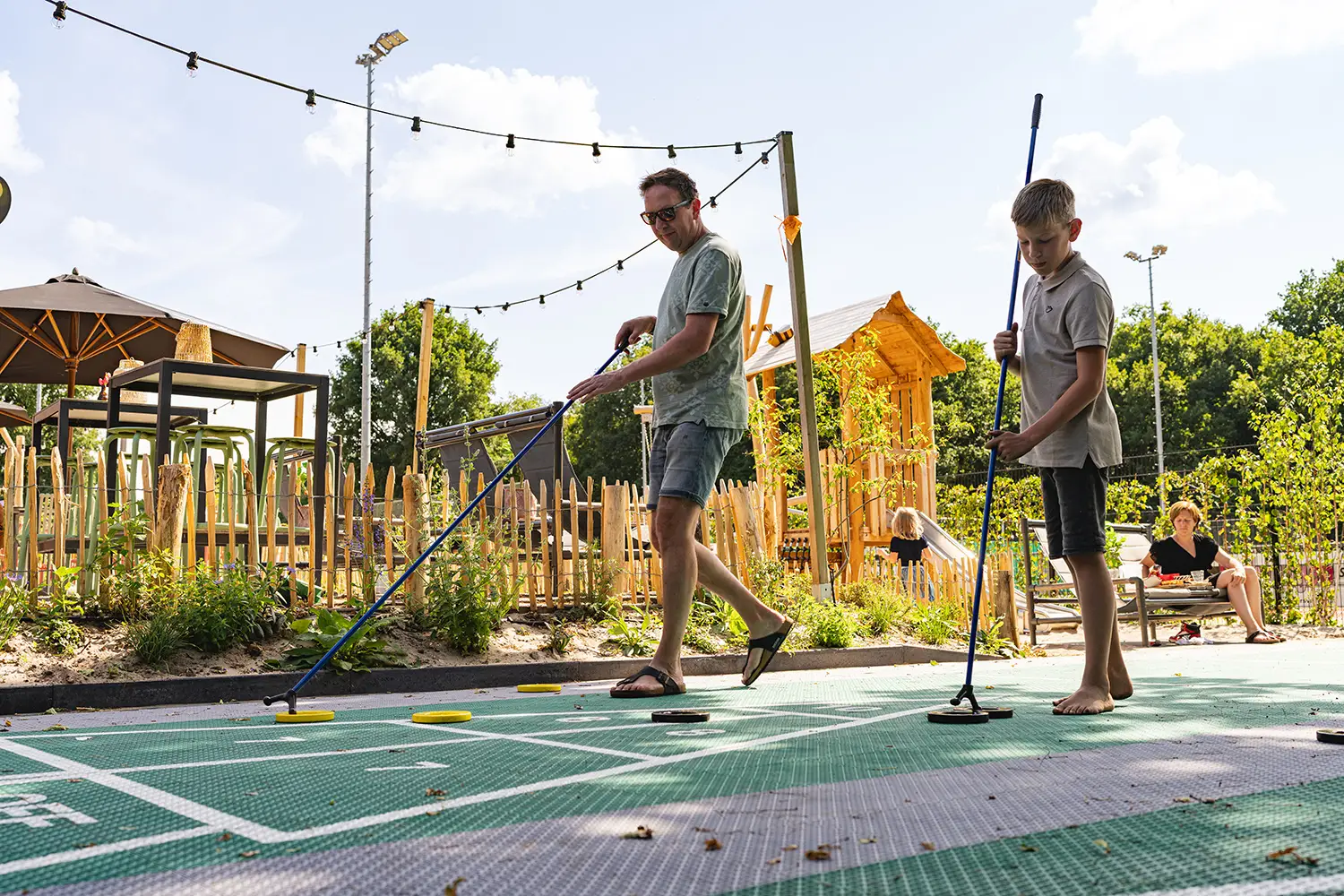 Vader en zoon spelen Floorshuffle op een zonnige dag bij De Hoge Heide