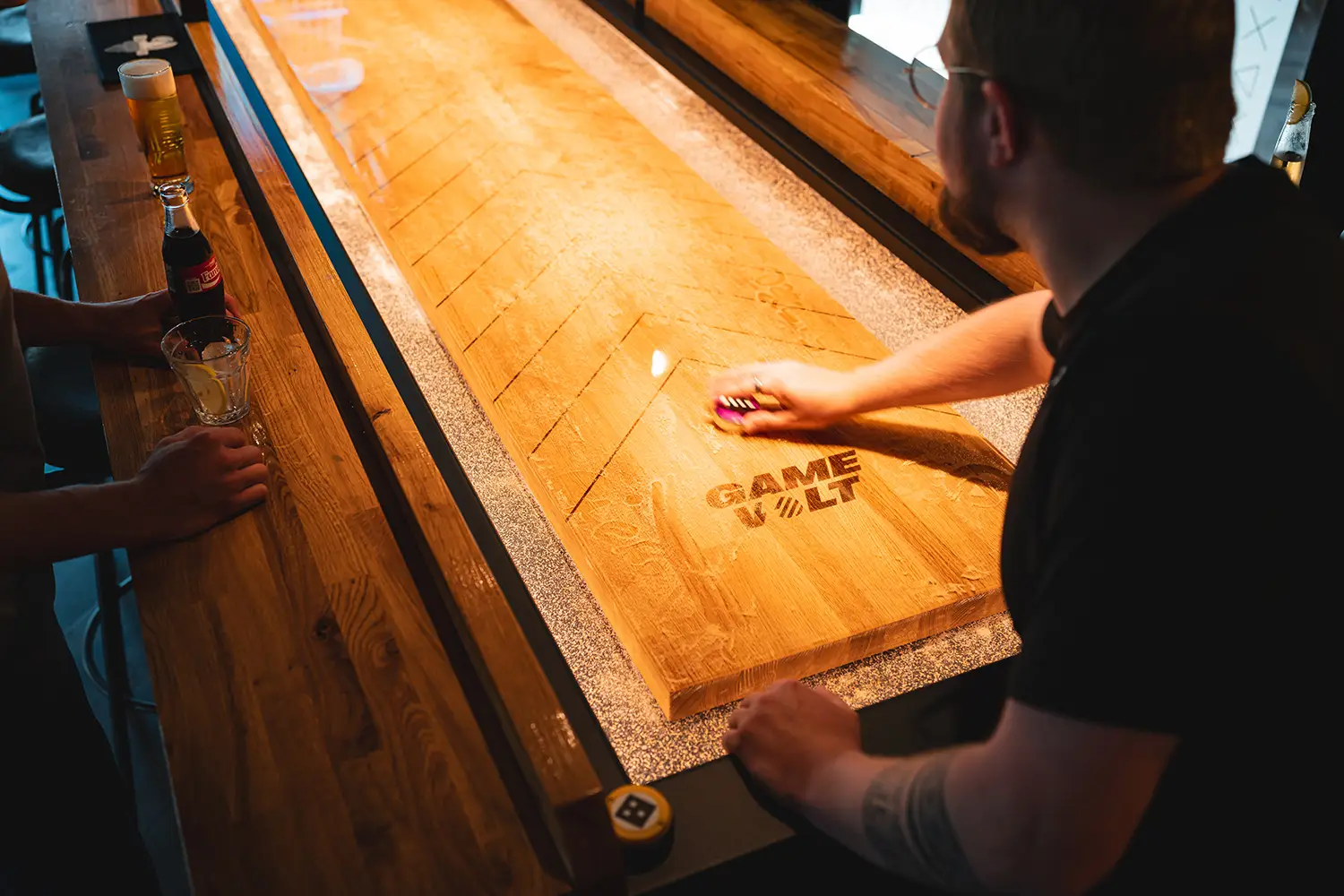 Een man die de schijven over de Supercharged Shuffleboard schuift.
