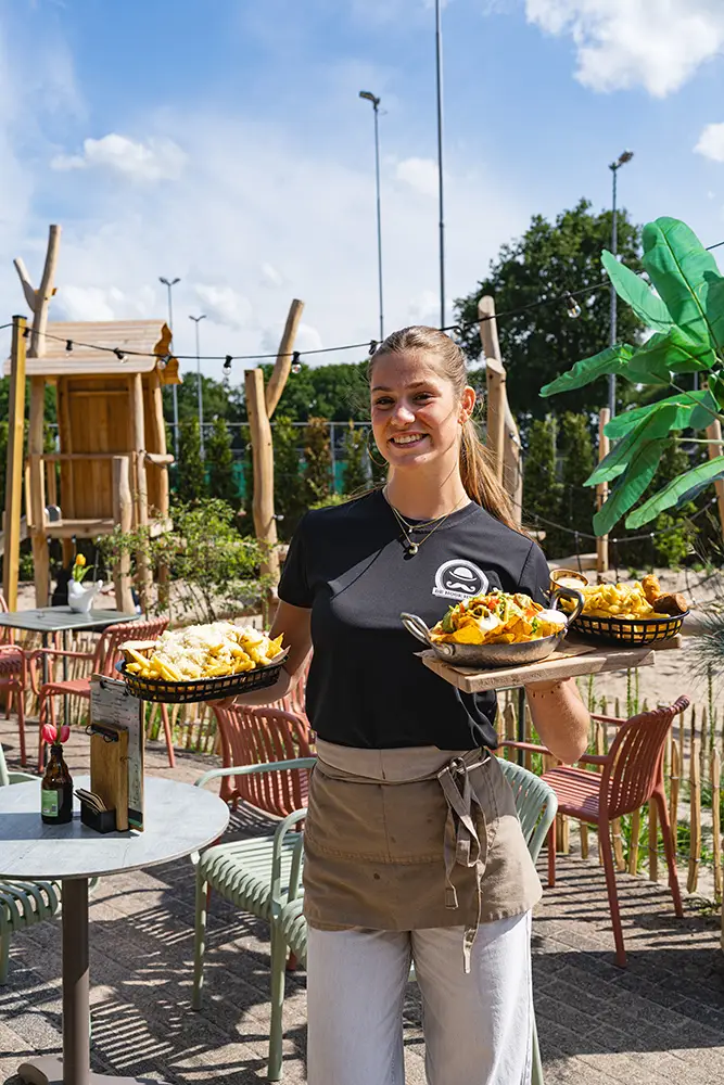 Vriendelijke vrouwelijke bediening van De Hoge Heide met lekkere bites in haar hand.