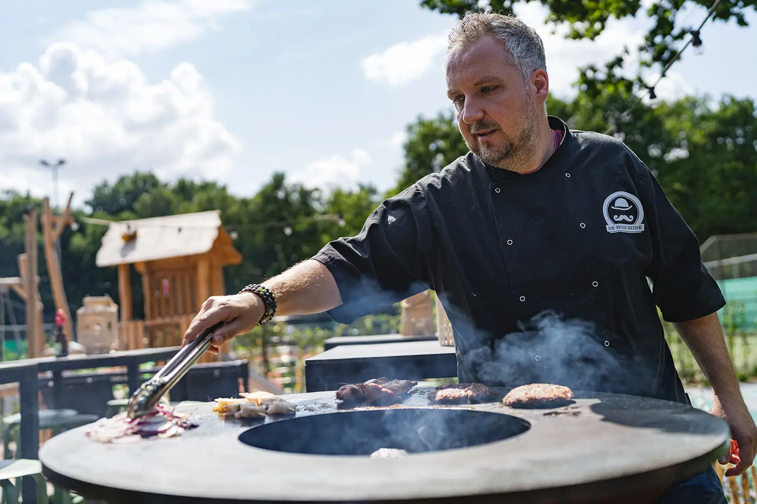Kok van De Hoge Heide aan een grote ronde BBQ