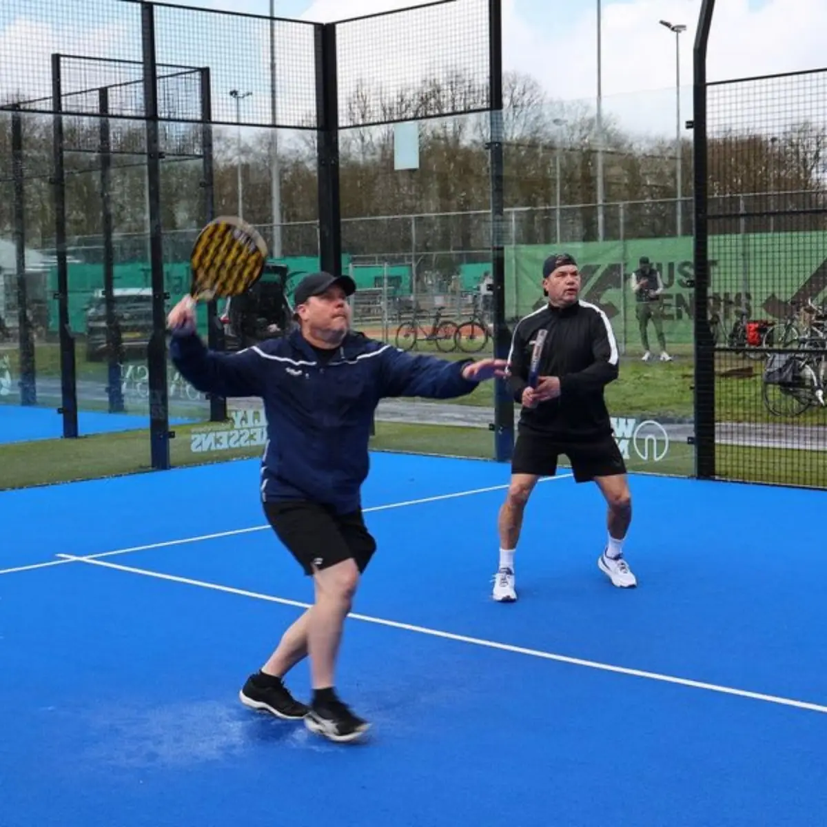 Twee heren die buiten padellen op de padelbaan van TPV De Hoge Heide